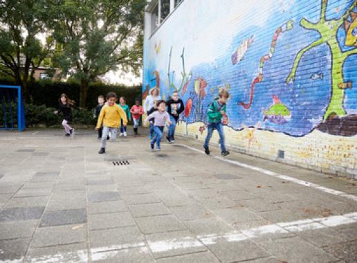 Decoratieve foto van leerlingen die over het schoolplein rennen
