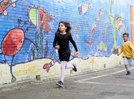 Twee kinderen rennen over het schoolplein langs een muur met een muurschildering