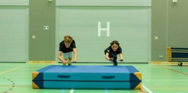 Decoratieve foto van twee leerlingen die op een mat springen